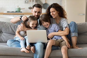 family of four watching laptop and laughing